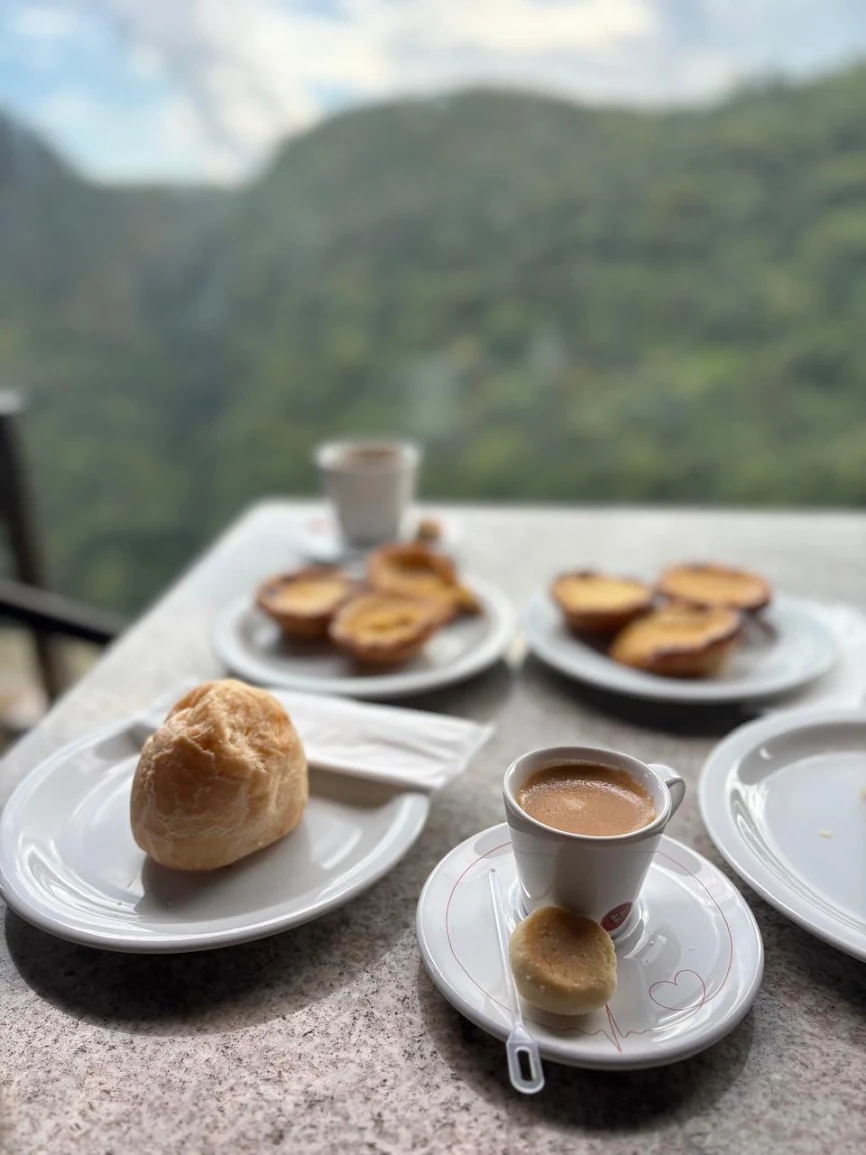 Mesa com pastéis de nata e café diante do vale da Mata Atlântica